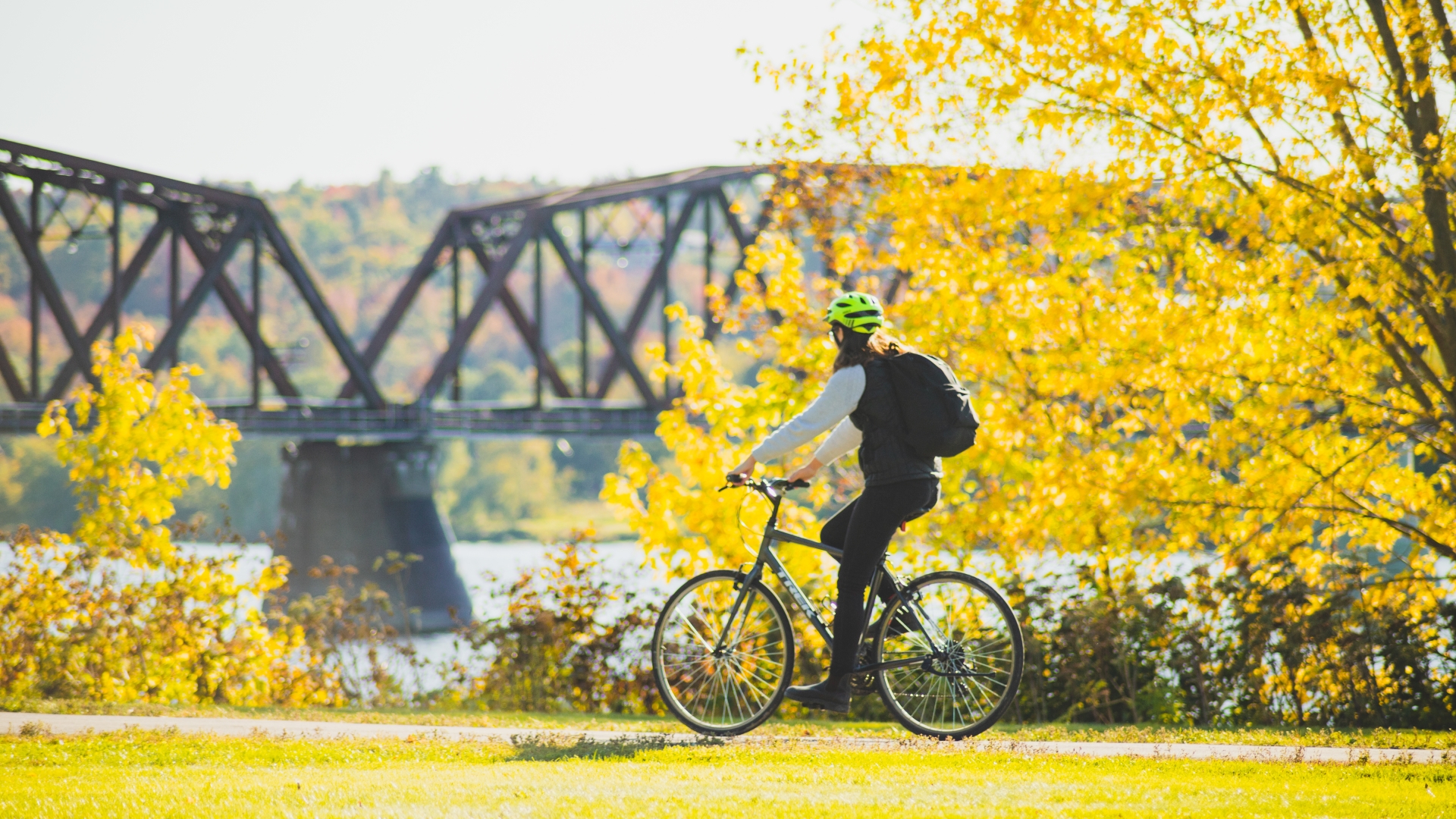 Women biking in Fall with the Bill Thrope Walking Bridge in Background