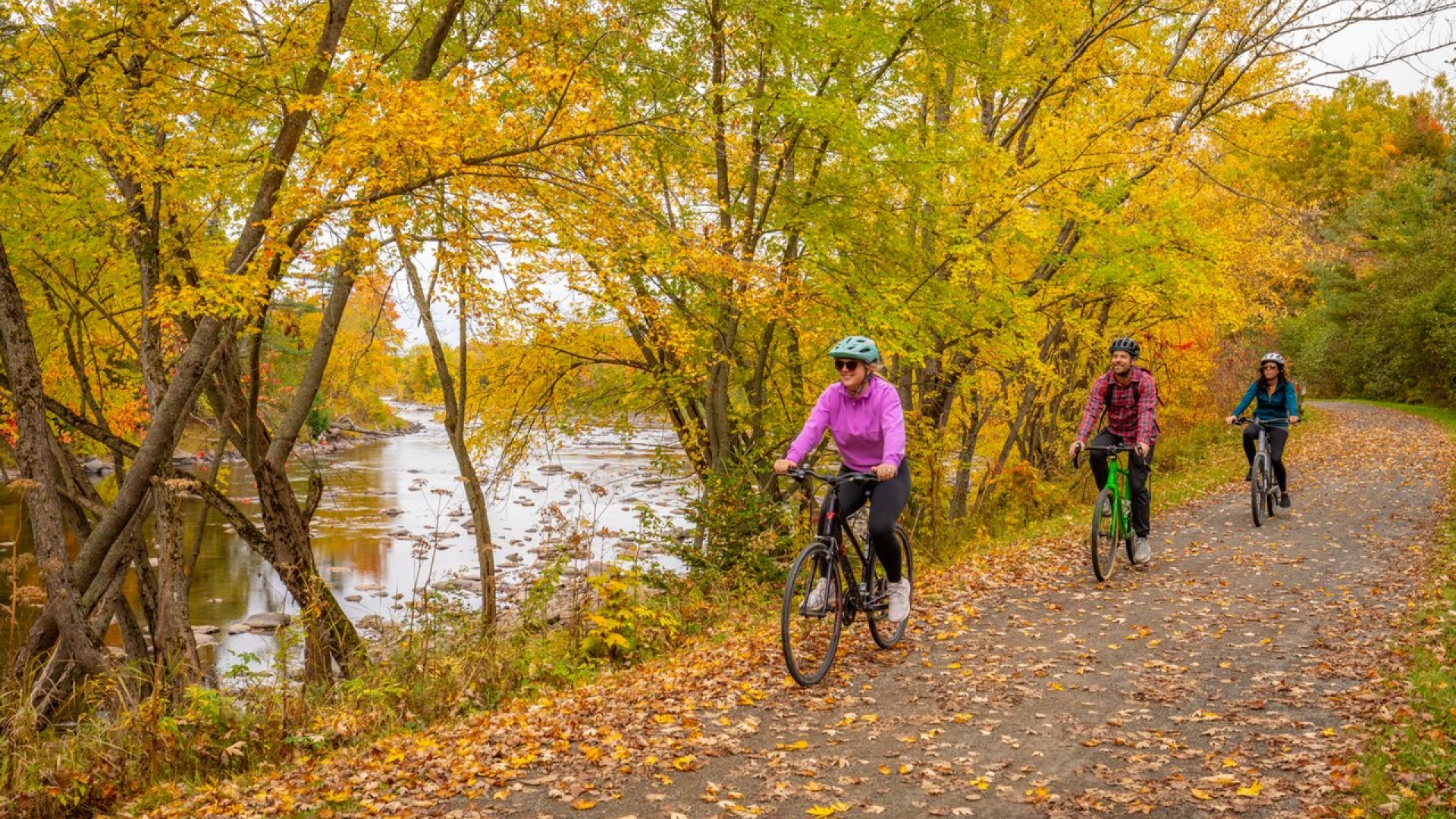 Three bikers on a trail next to river