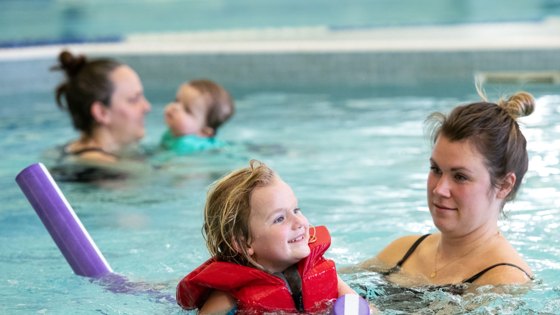 Two moms swimming with their kids