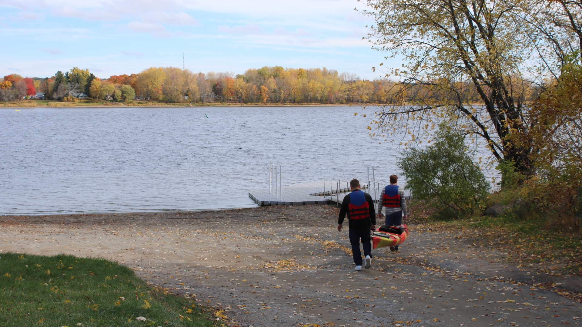 Two men carrying kayak to the river