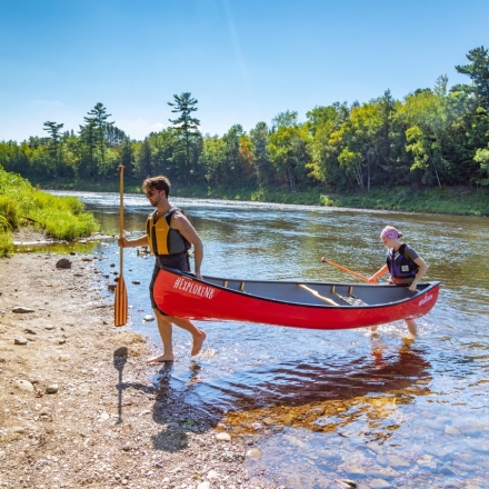 Canoeing_Man-And-Woman-Carrying-Canoe-Out-Of-Water