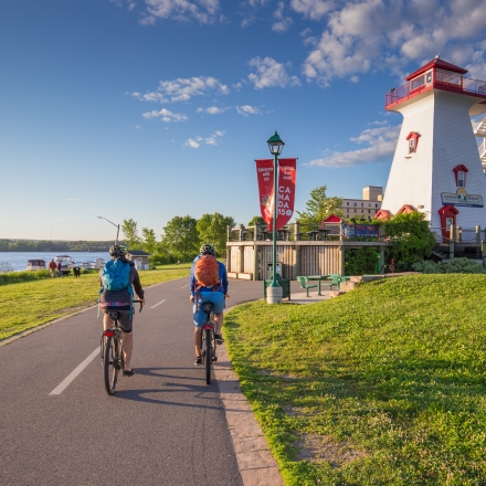 Biking on trail next to river and lighthouse