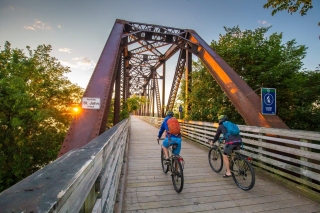 Two bikers on Bill Thrope Walking Bridge at sunset