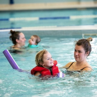 Two moms swimming with their kids