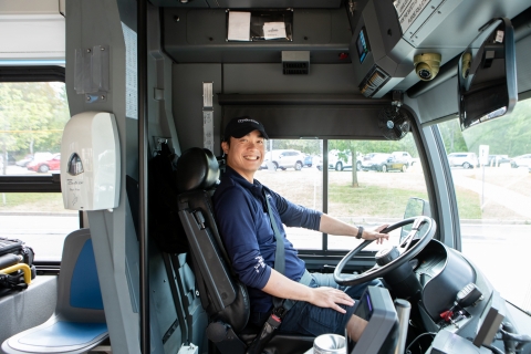 transit bus operator sitting in the bus drivers seat smiling 
